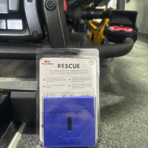 A close-up view of the 'Buckle Boss Rescue' tool, a specialized device designed for quickly releasing seat belts in emergency situations.