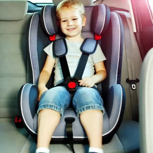 An-older-child-sitting-in-a-car-seat-using-a-5-point-harness.-The-child-looks-happy-and-comfortable-and-the-car-seat-is-securely-installed-in-the-bac